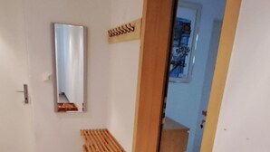 En hall med ett klinkergolv, en träbänk, en spegel och en dörr som leder till ett annat rum.