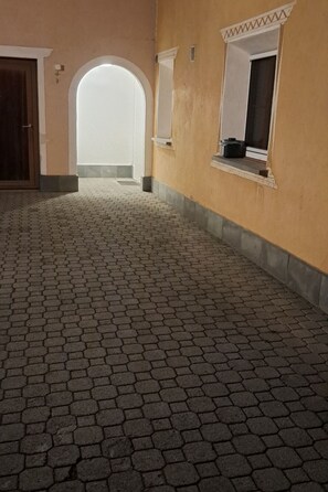 Ein Korridor mit sechseckigem Steinbelag, einer Holztür und einem Fenster mit weißem Rahmen.