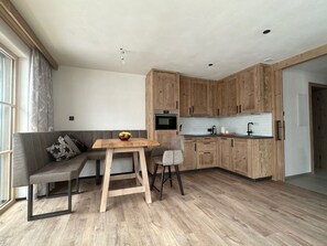 A modern kitchen with wooden cabinets, a built-in oven, and a dining area with a table and chairs. - Chalet d'Mot, (Samnaun-Ravaisch) by Interhome (Samnaun-Ravaisch)