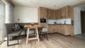Una cocina moderna con armarios de madera, una mesa de comedor y un sofá gris.