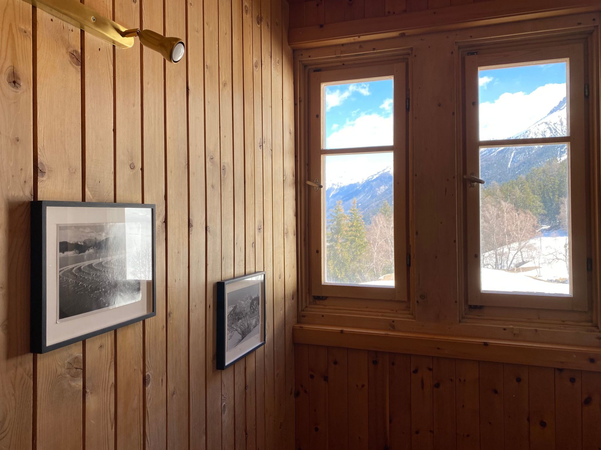 Un intérieur en bois avec deux fenêtres donnant sur les montagnes.