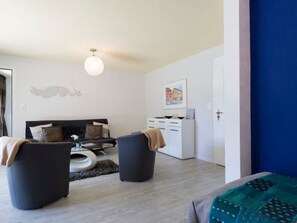 A modern bedroom with a bed, two armchairs, a small table, and a dresser. - Chasa Diala, (Scuol) by Interhome (Scuol)