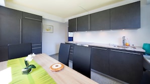 Eine moderne Küche mit dunklen Schränken, einer Marmorarbeitsplatte und einem Essbereich mit einer grünen Tischdecke und einem Kuchen.