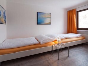 Una habitación moderna con una cama, una mesita y un ventanal con cortinas.