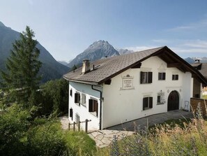 En vit byggnad med ett sluttande tak, en skylt med texten ”Hotell” och en bergskedja i bakgrunden.