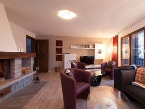 A modern living room with a fireplace, a television, and comfortable seating. - Ferienhaus Chasa Diala, (Scuol) by Interhome (Scuol)