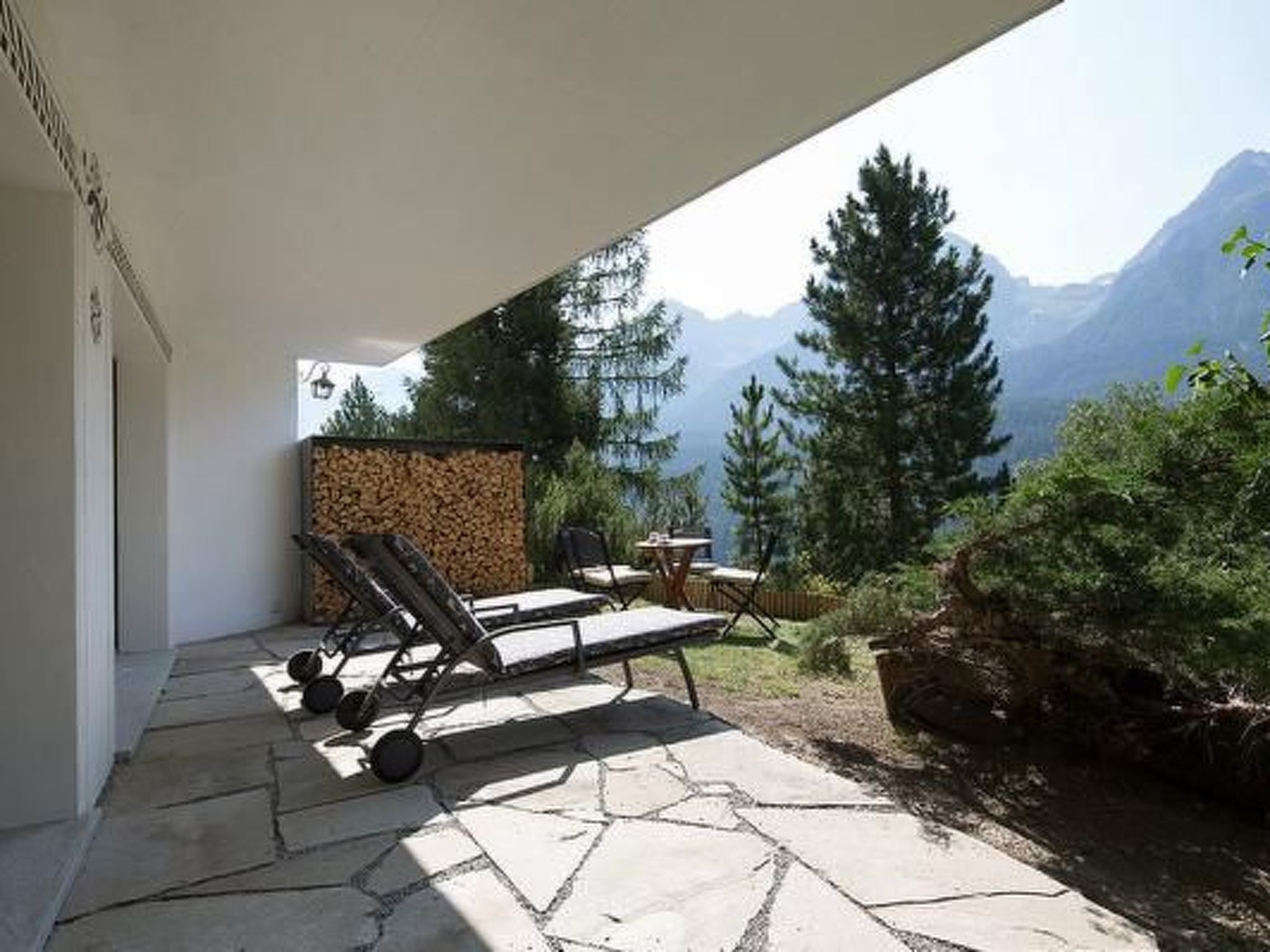 A patio with a stone floor, a lounge chair, and a table.