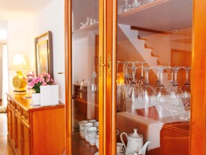 Ein Zimmer mit einem Holzkabinett, einer Vitrine mit Teekannen und Tassen sowie einem Spiegel an der Wand.
