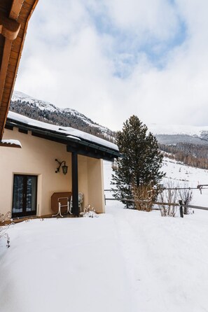 Paisatge cobert de neu amb un edifici que té un balcó i un teulat també cobert de neu.