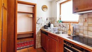 A kitchen with wooden cabinets, a tiled backsplash, a stove, and a window. - Ferienhaus Grundschera, (Brail) by Interhome (Brail)