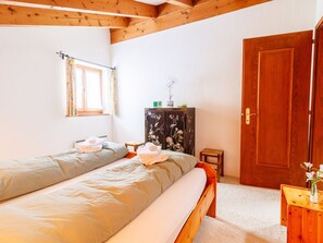 Ein Schlafzimmer mit einem Bett, einem Holzschrank, einem kleinen Tisch und einer Tür.