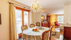 A dining area with a chandelier, a table set with fruit, and a view through the window. - Ferienhaus Grundschera, (Brail) by Interhome (Brail)