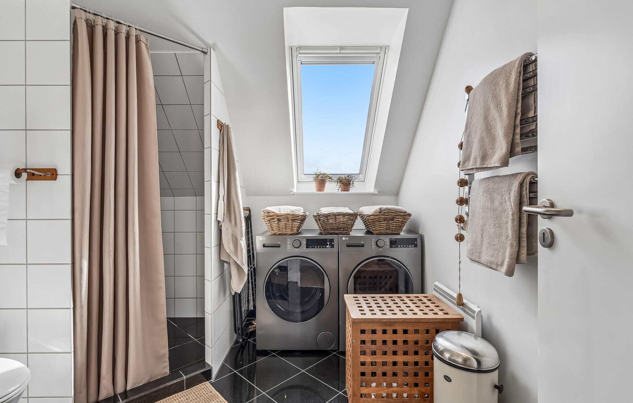 A compact laundry room with a washing machine, dryer, and a small window above the dryer.