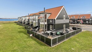 A modern residential building with multiple units, a covered patio, and a view of the sea. - Nice home in Juelsminde with harbor view (Juelsminde)
