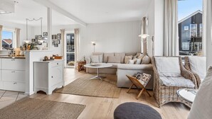 A modern living room with a sofa, a dining table, and a kitchen area. - Nice home in Juelsminde with harbor view (Juelsminde)