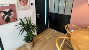 Um interior moderno com chão de madeira, uma mesa de jantar com cadeiras, uma porta preta e obras de arte nas paredes.