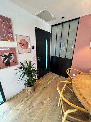 Ein modernes Interieur mit Holzboden, einem Esstisch mit Stühlen, einer schwarzen Tür und Wandbildern.