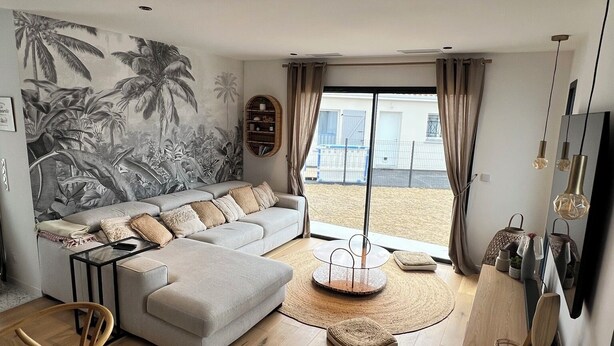 Uma sala de estar moderna com um sofá seccional, um espaço de refeições e vista para o exterior.