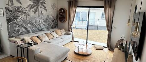 A modern living room with a sectional sofa, a dining area, and a view of the outdoors.