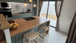 Cozinha moderna com ilha central, luminárias pendentes e vista para o exterior.