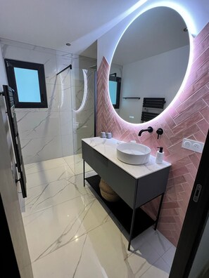 A modern bathroom with a marble floor, a round mirror with a pink accent wall, and a built-in sink. - 4-Bedroom House with Heated and Air-Conditioned Pool in Dax (Tercis-les-Bains)