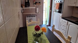 Eine Küche mit Esstisch, Stühlen, einer Kaffeemaschine und einem Kühlschrank.