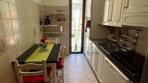 Eine kleine Küche mit Esstisch, Stühlen und einem Kühlschrank.
