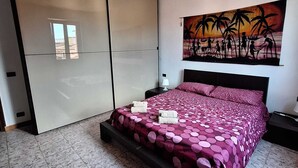 Ein Schlafzimmer mit Bett, Nachttisch, einem Gemälde und einem Kleiderschrank.
