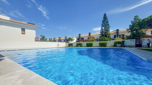 Une piscine à l’eau d’un bleu limpide, entourée de bâtiments et de verdure.