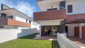 Une maison à deux étages dotée d’un balcon, d’une terrasse couverte et d’une pelouse bien entretenue.