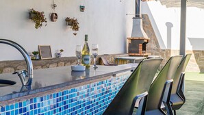 An outdoor bar area with a tiled backsplash, bar stools, a wine bottle, and a glass. - Lovely home in Pechina (Pechina)