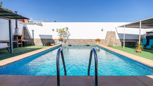 A swimming pool with a stone wall, a grill, and outdoor seating. - Lovely home in Pechina (Pechina)