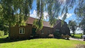 A brick house with a tiled roof, a grassy lawn, and a bench. - Vacation at the Horse Farm—Pets Welcome! (Jade)