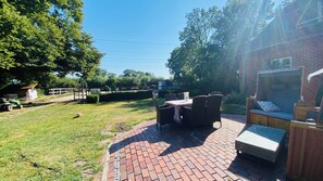 A patio area with a brick floor, outdoor furniture, and a view of a grassy yard with trees. - Vacation at the Horse Farm—Pets Welcome! (Jade)