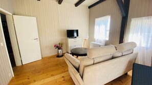 A room with a sofa, a television, a small table, and a decorative vase. - Vacation at the Horse Farm—Pets Welcome! (Jade)