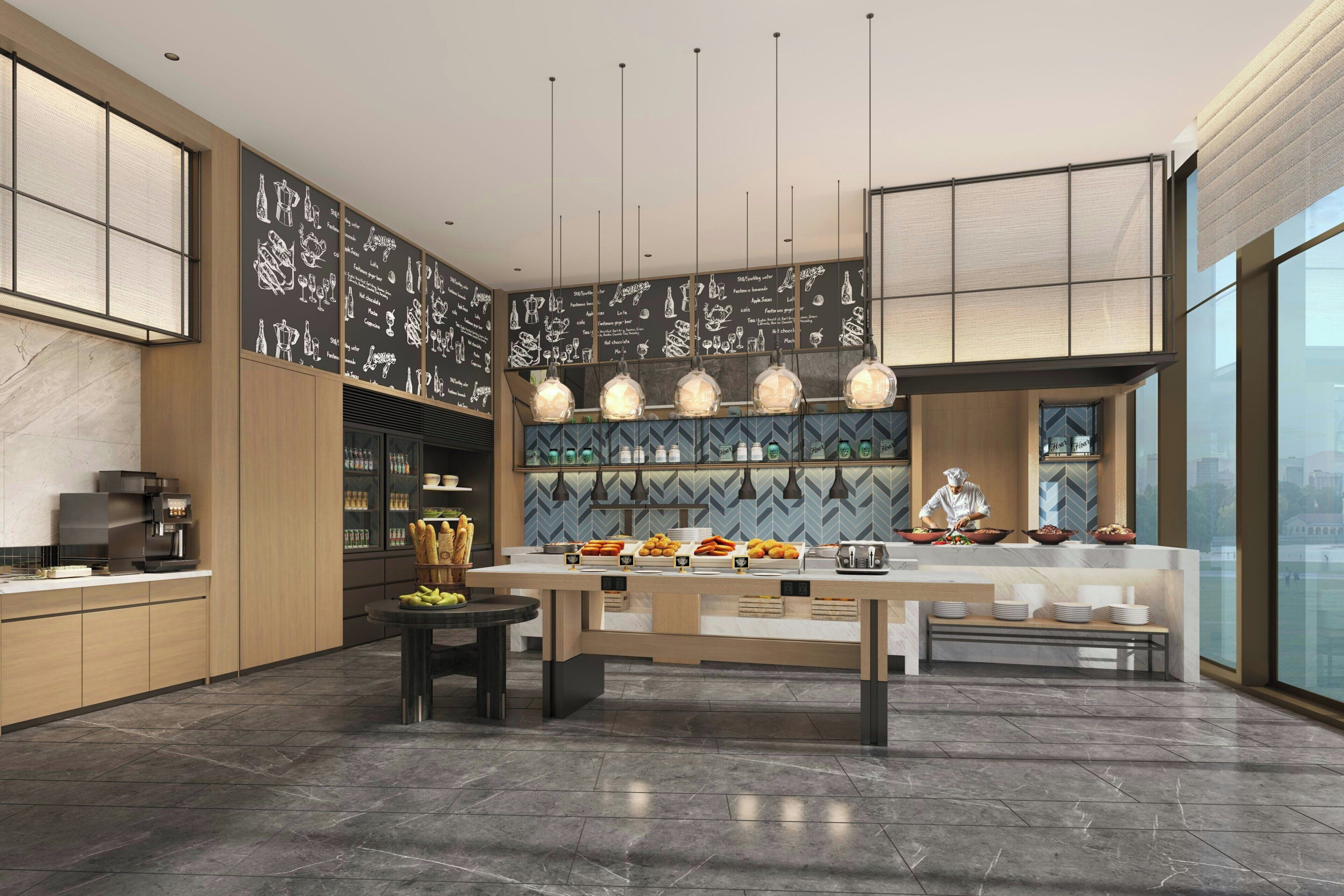 Una cocina moderna con una isla central, una cafetera y un chef preparando comida.