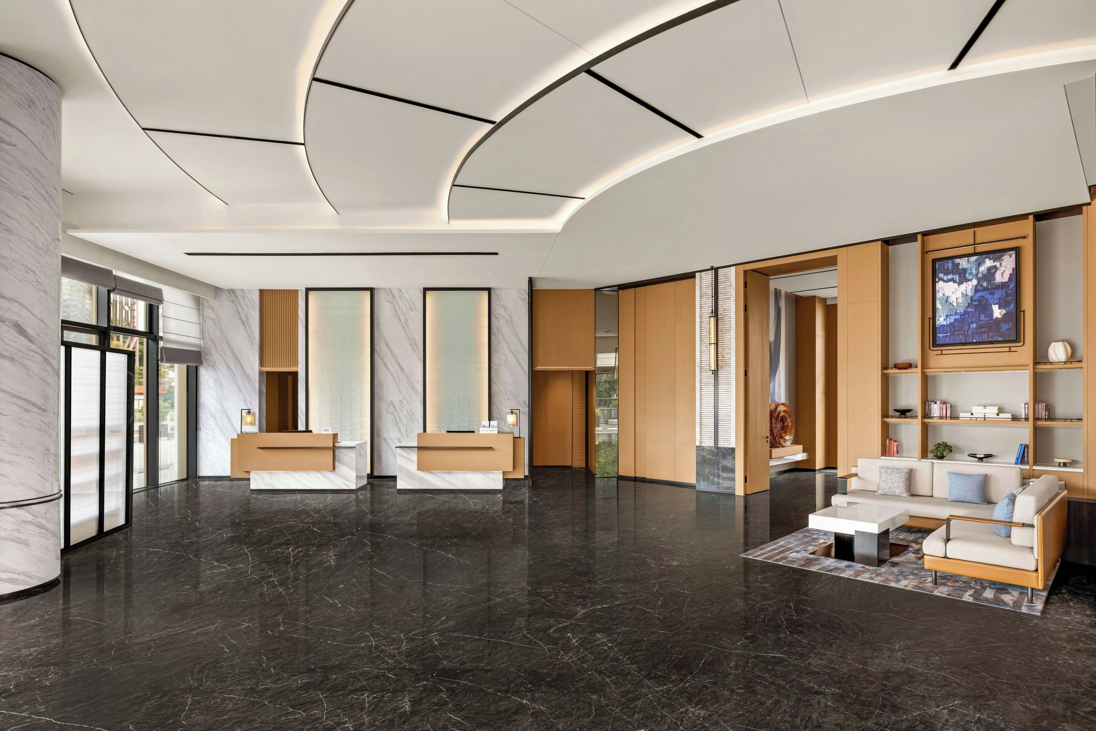 A modern lobby with a reception desk, seating area, and a large window.