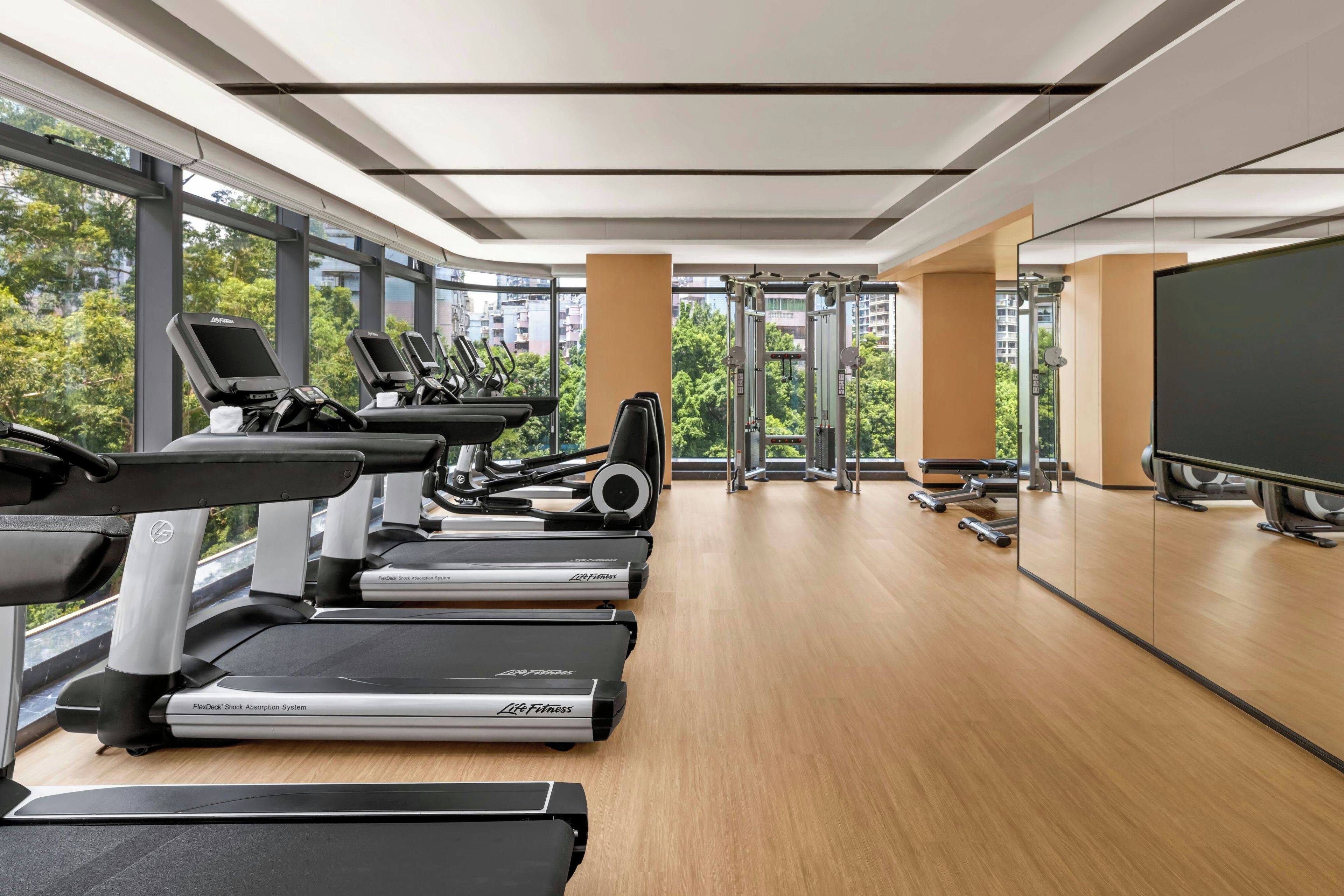 A modern gym with treadmills, elliptical machines, and weight equipment.
