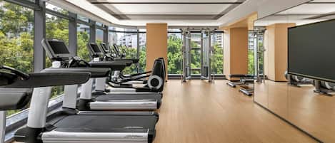 Un gimnasio moderno con cintas de correr, elípticas y equipo de pesas.