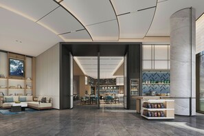 Un hall d’hôtel moderne doté d’un espace salon, d’un bar et offrant une vue sur la salle à manger.