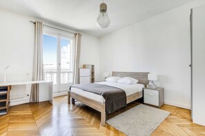 Ein Schlafzimmer mit Bett, Nachttischen, einem Schreibtisch und einem Heizkörper.