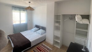 A bedroom with a bed, a wardrobe, a hanging light fixture, and a window. - 4-bedroom house within a 5-minute walk of the beach and shops (Sainte-Marie-la-Mer)