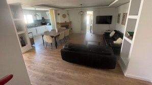 A spacious living area with a sofa, dining table, and chairs. A television is mounted on the wall. - 4-bedroom house within a 5-minute walk of the beach and shops (Sainte-Marie-la-Mer)