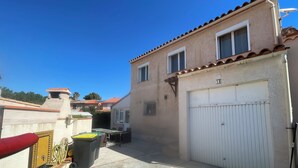 A residential building with a garage, a patio with outdoor furniture, and a small chimney. - 4-bedroom house within a 5-minute walk of the beach and shops (Sainte-Marie-la-Mer)