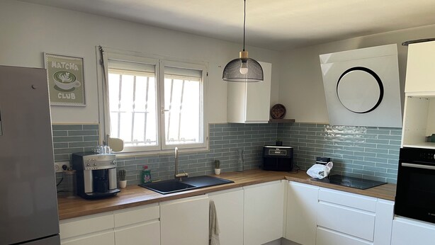 A modern kitchen with white cabinets, a coffee machine, a sink, and a window with blinds. - 4-bedroom house within a 5-minute walk of the beach and shops (Sainte-Marie-la-Mer)