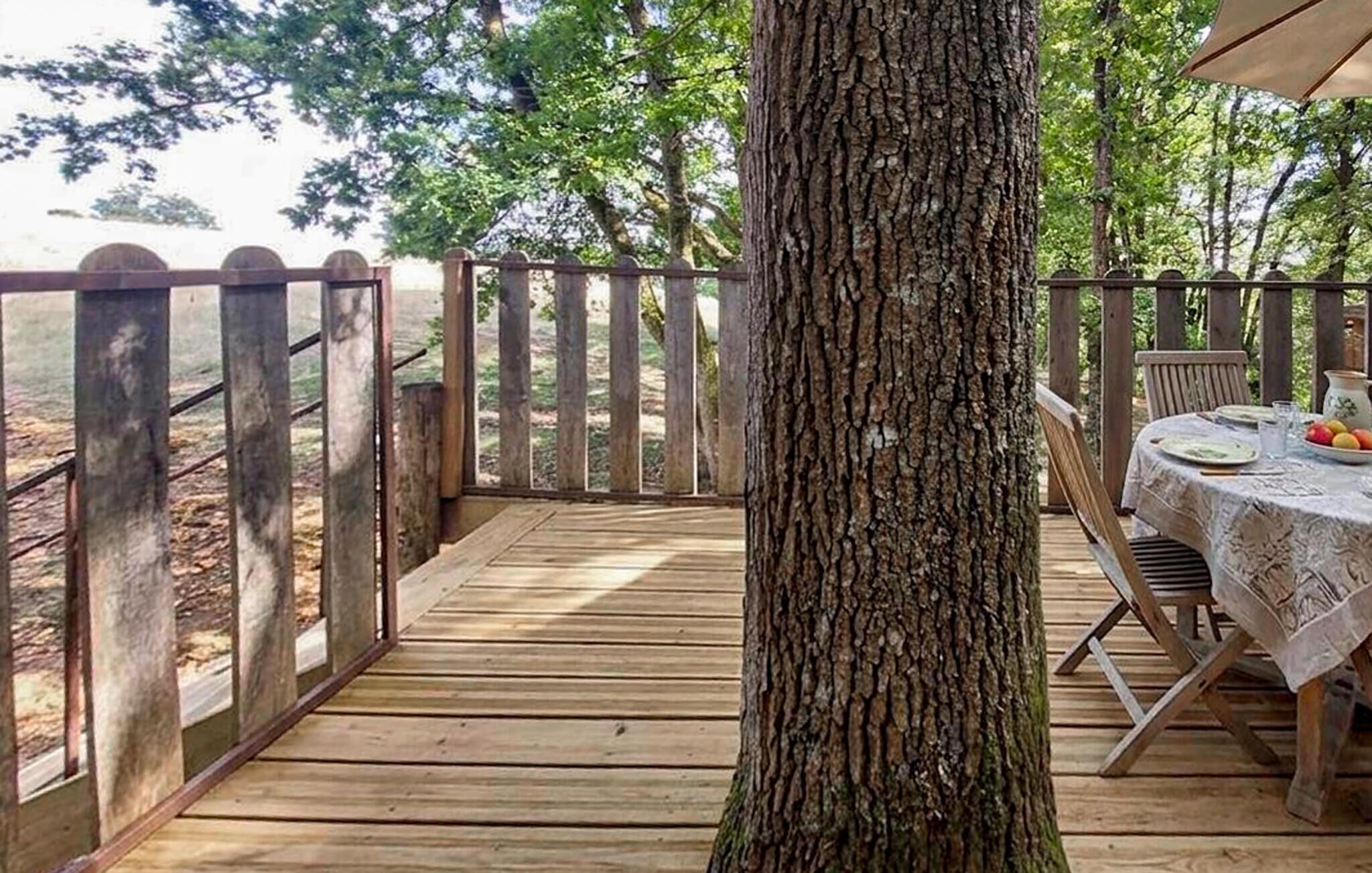 Une terrasse en bois avec une table et des chaises, entourée d’une clôture en bois.