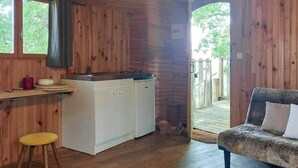 Een houten interieur met een kitchenette, een bank en uitzicht op de omgeving.