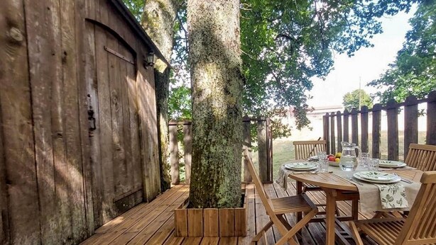Een houten terras buiten, met een eettafel en stoelen eromheen.