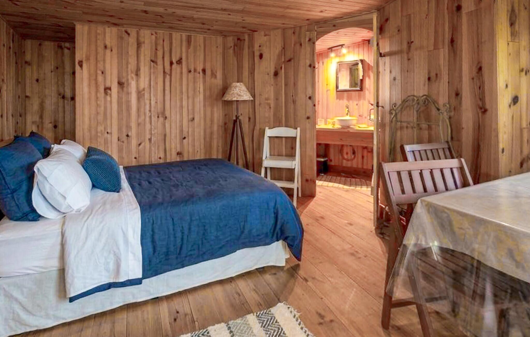 Een houten kamer met een bed, een stoel, een tafel en een spiegel.