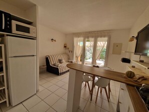 Eine kompakte Küche mit Mikrowelle, Kühlschrank und einem Essbereich mit Holztisch und Stühlen.